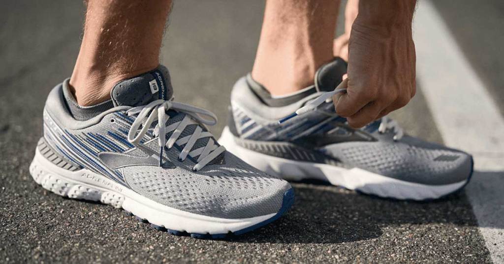 man lacing up brooks adrenaline shoes