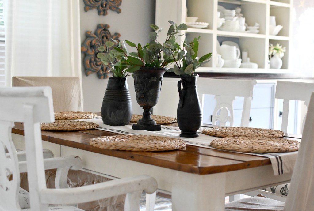 dining table with black vases and greenery