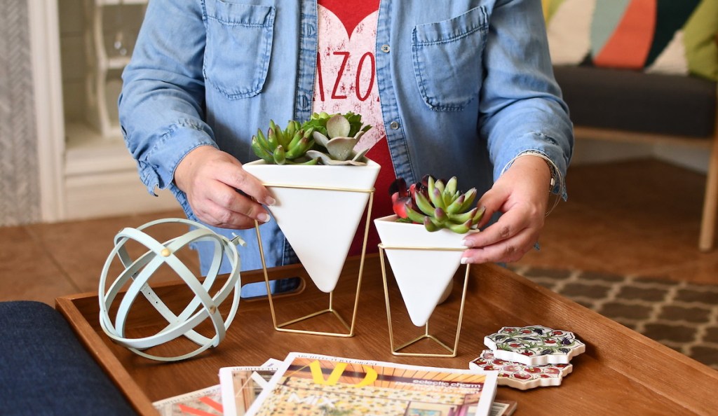 woman holding two white geometric vases with succulents 