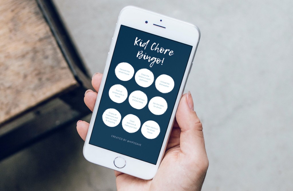 phone holding a phone with kid chore bingo chart on screen