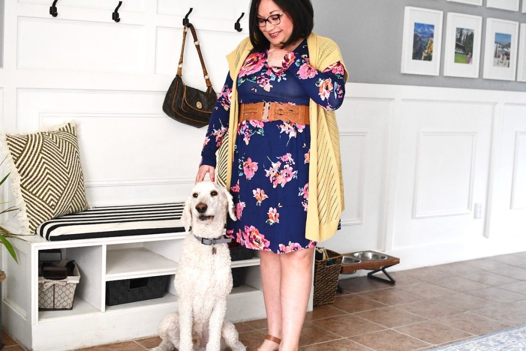 woman wearing floral dress in foyer petting dog