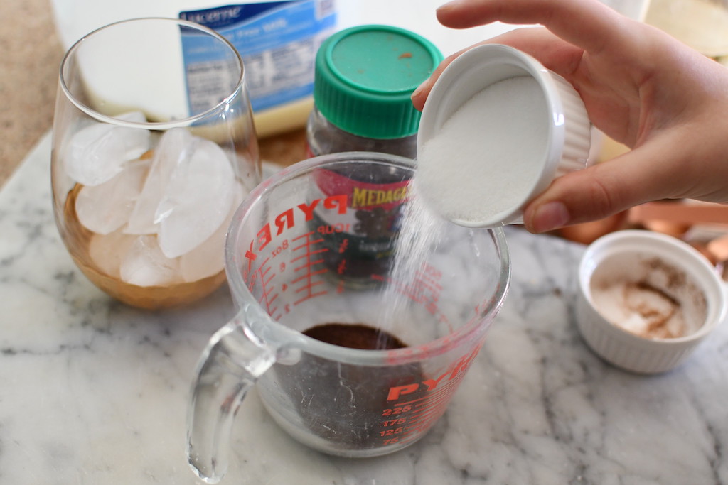 making whipped iced coffee and adding sugar to measuring cup 