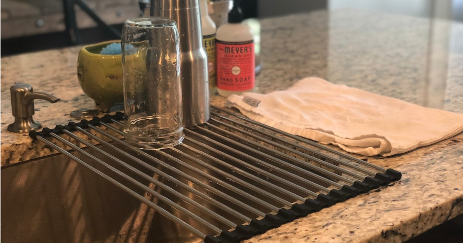 metal drying rack sitting over kitchen sink with two wet cups sitting on top