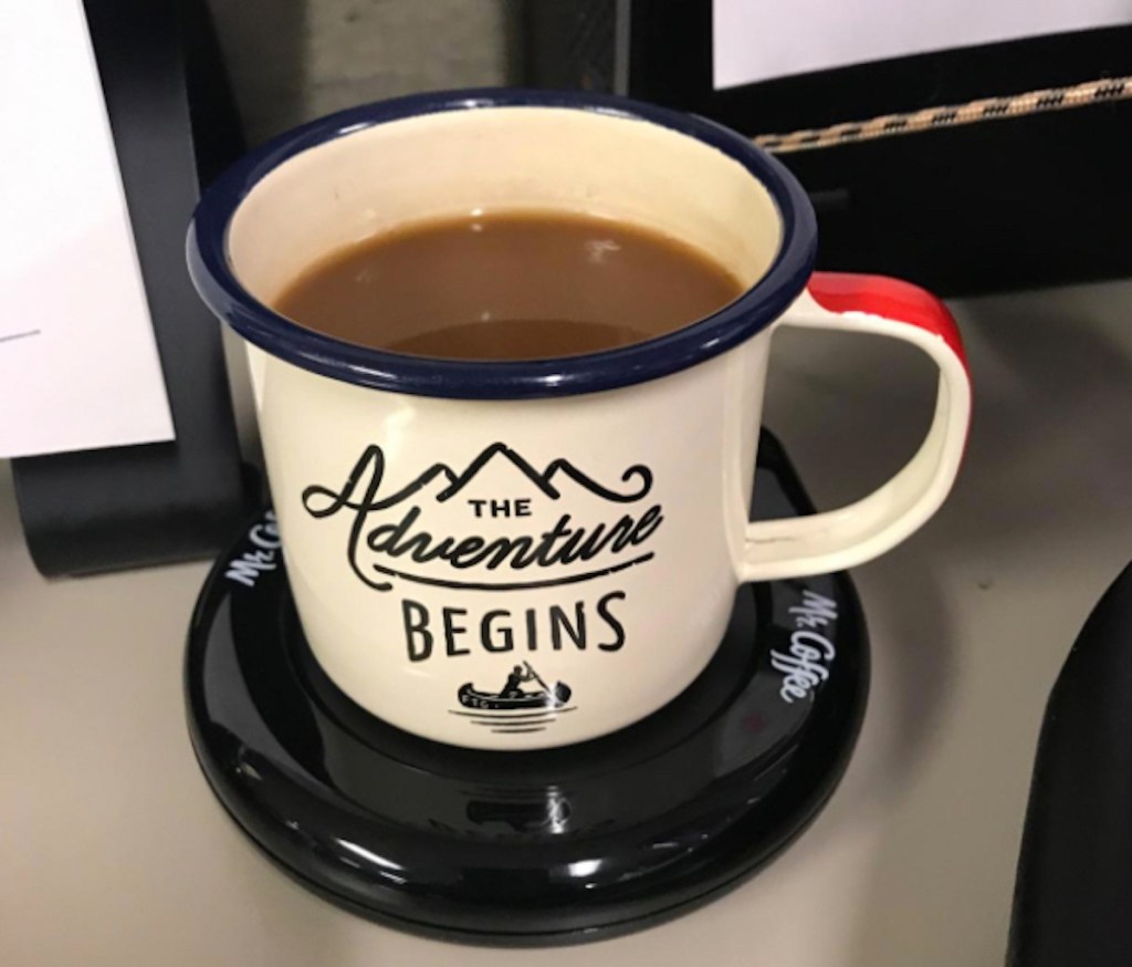 adventure mug sitting on black mug warmer on desk