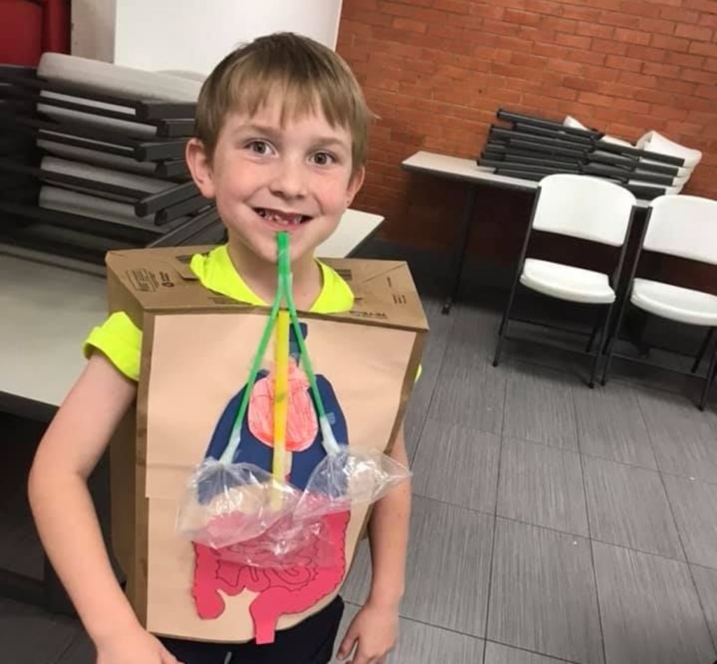 boy wearing paper bag with cutouts of organs glued on it