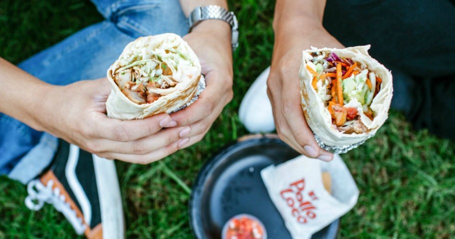 hands holding burritos