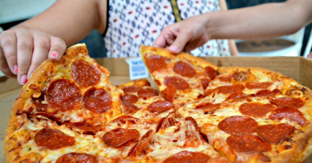 Kids grabbing slices of pizza from a pizza box