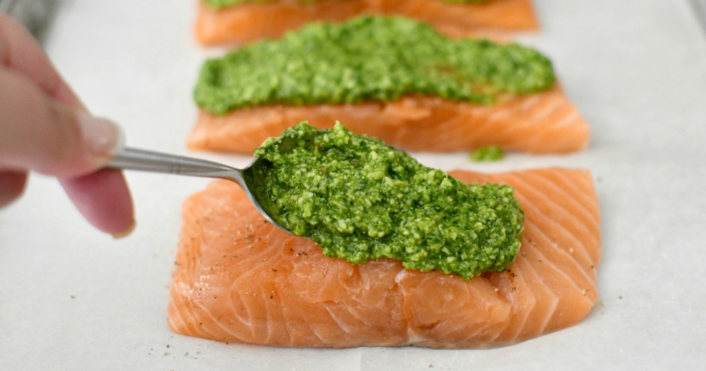 putting cilantro pesto on salmon 