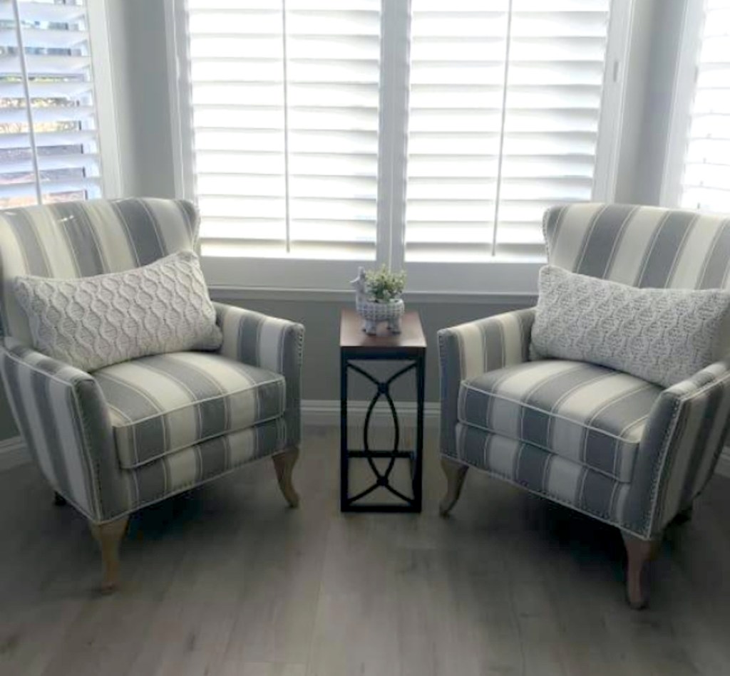 two stripe accent chairs sitting on wood floor in front of window with two white pillows