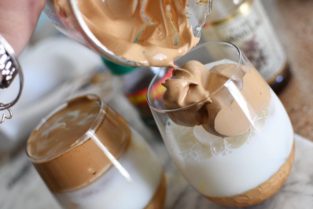 pouring whipped coffee in glass cup 