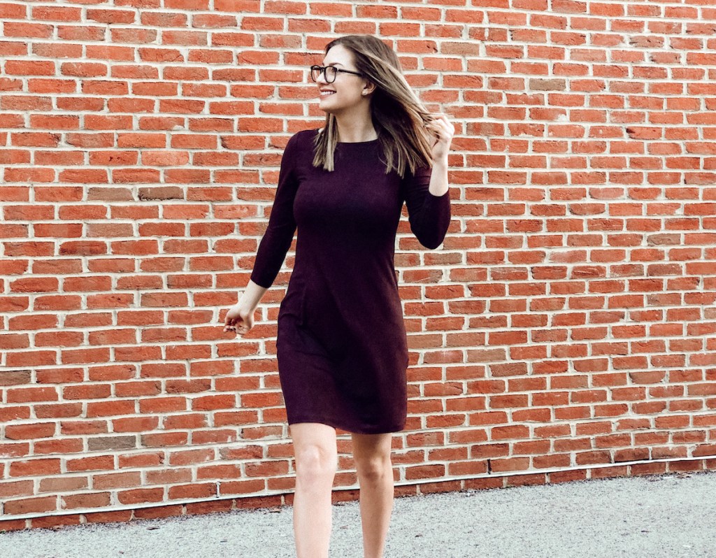 woman wearing dark purple dress in front of brick wall