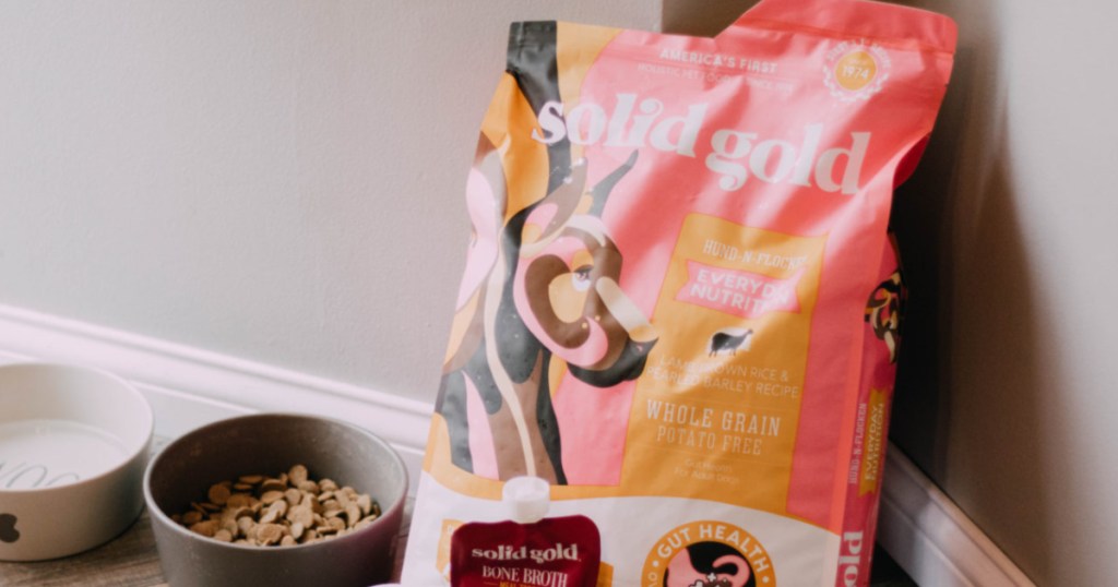 bag of solid gold dog food with dog bowls beside it