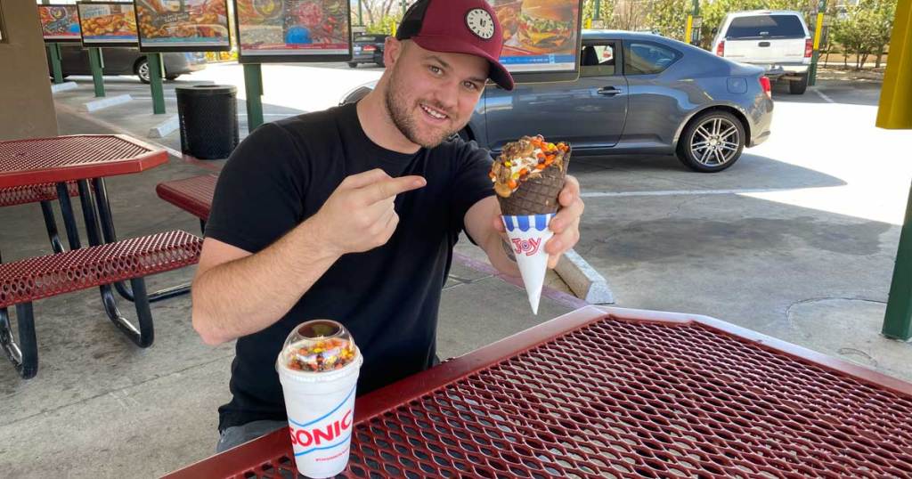 man holding a waffle cone and shake