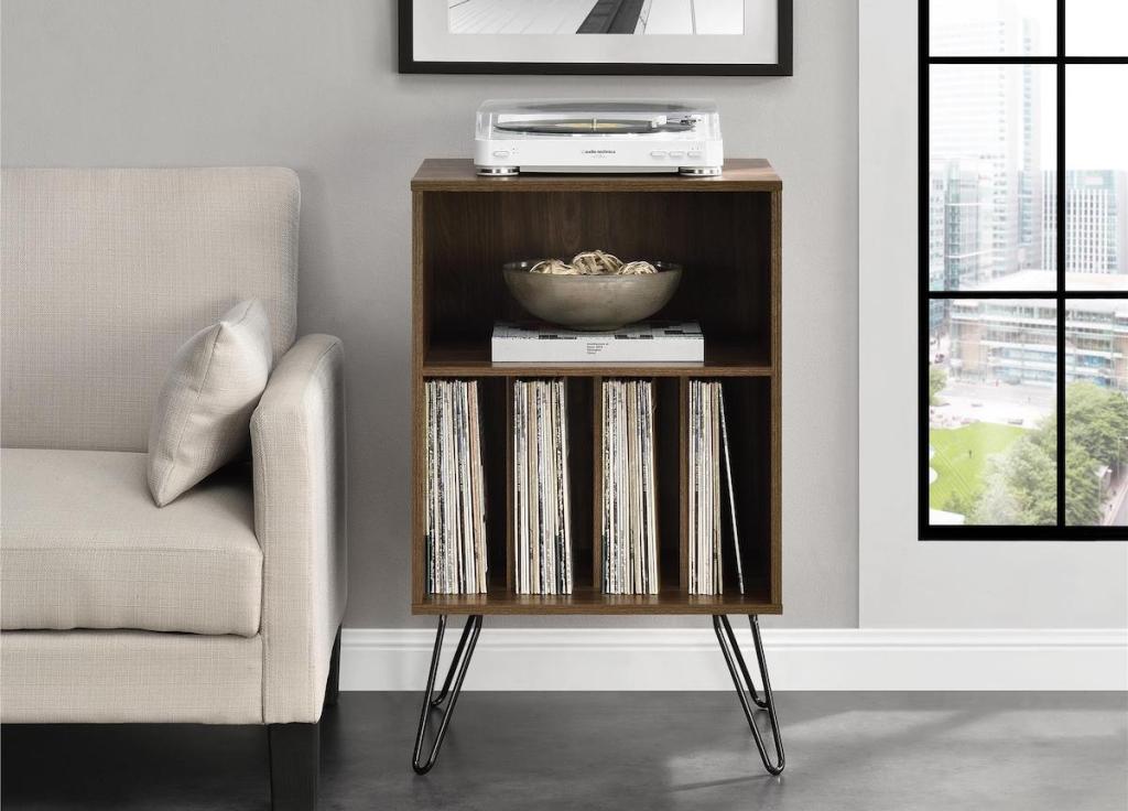 wood cabinet table with turntable on top and vinyl records on the bottom shelves