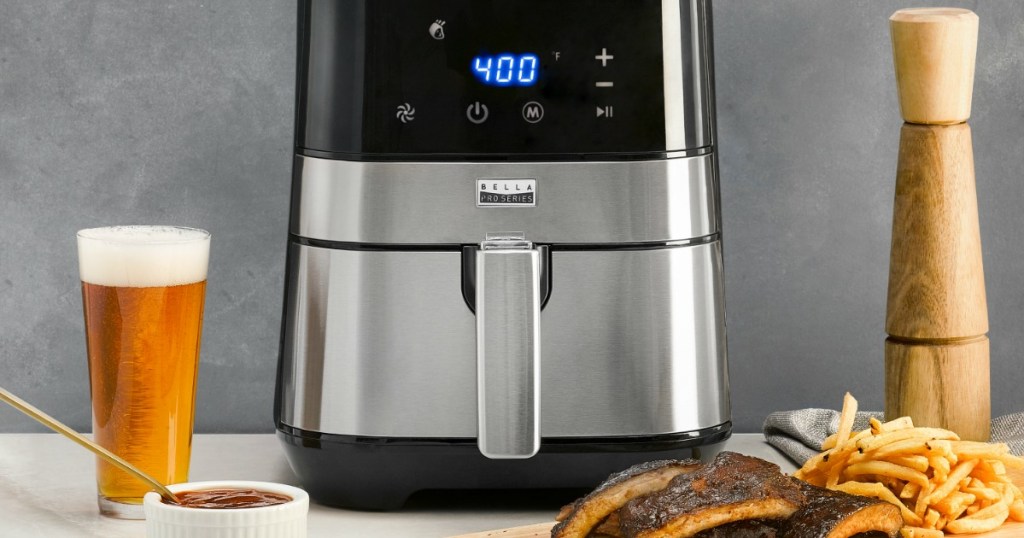 air fryer on counter next to a beer and a plate of ribs and fries