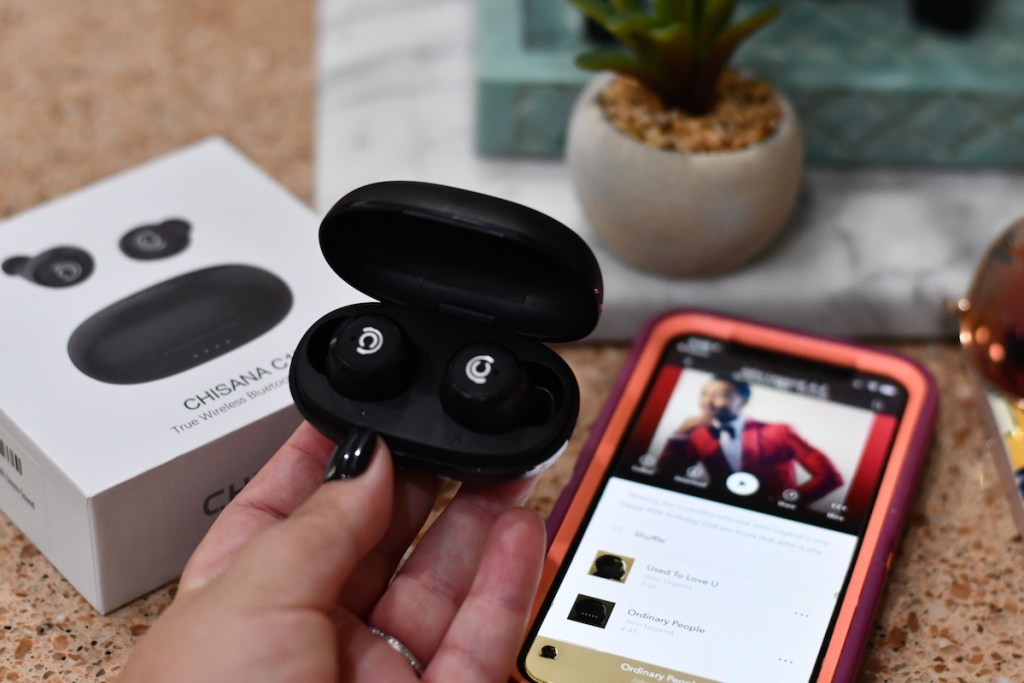 hand holding a pair of wireless earbuds in their case