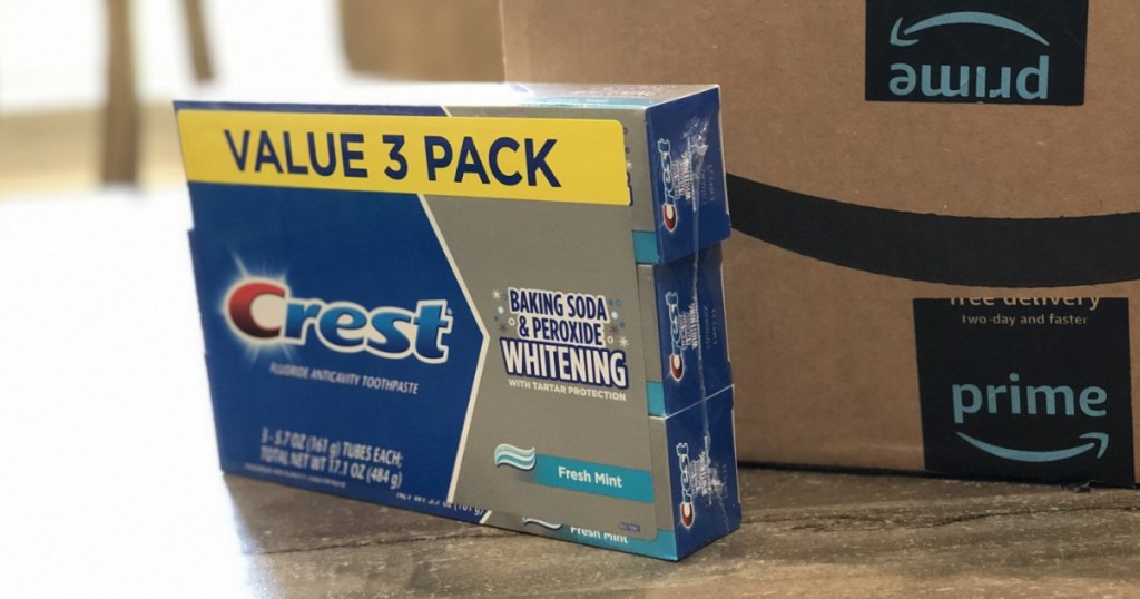 3 pack of Crest Toothpaste on table in front of Amazon box