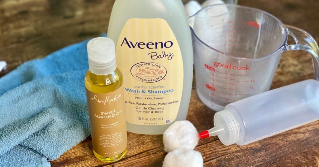 DIY makeup remover ingredients on a table with cotton balls, measuring cup, and an empty plastic bottle