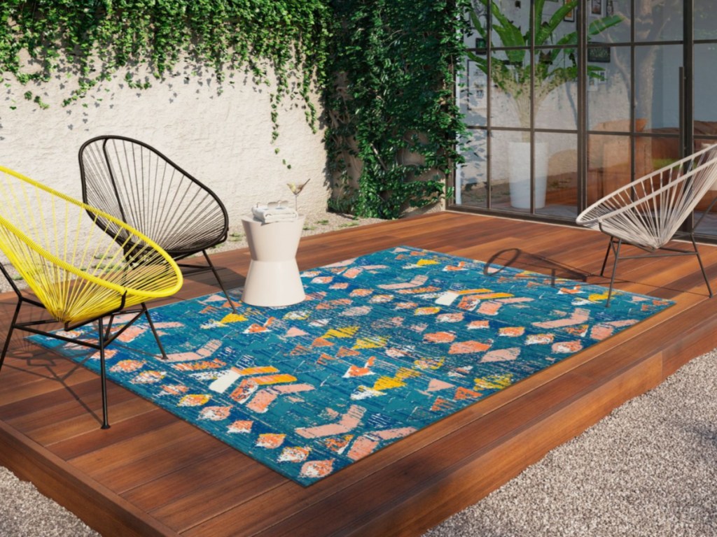 colorful blue rug on deck outdoors with black yellow and white chairs