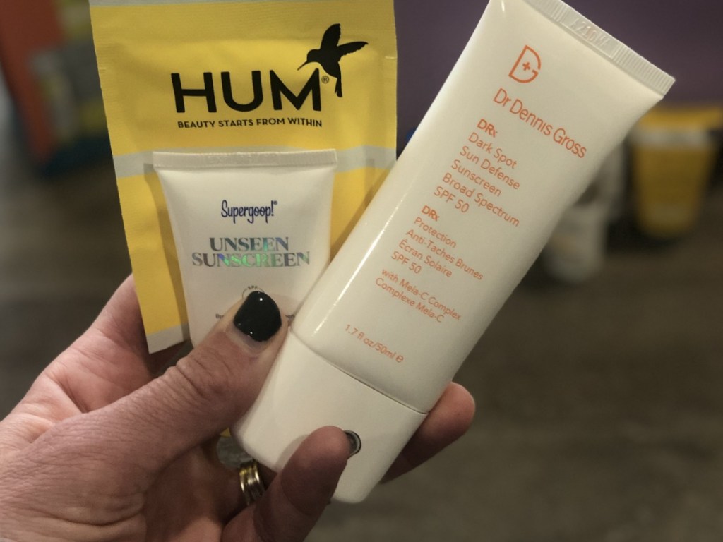 Woman holding bottles of Dr Dennis Gross Sunscreen and Supergoop Sunscreen