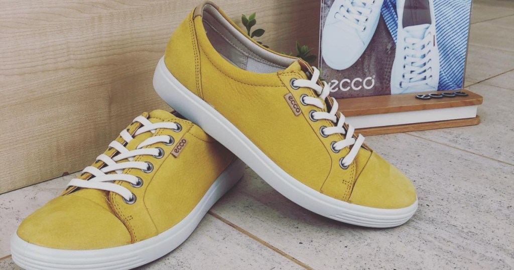 yellow women's sneakers sitting on floor in front of brand sign
