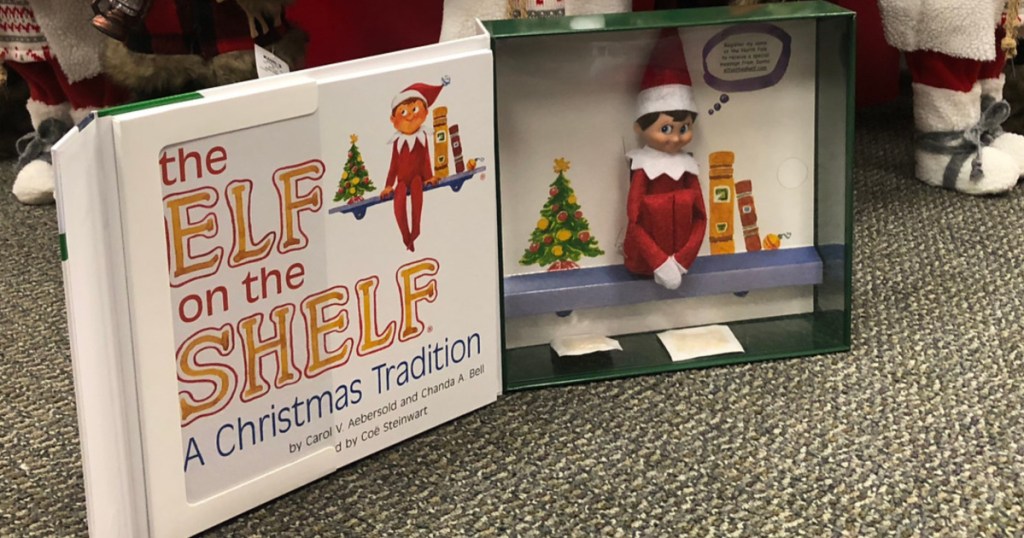 elf on the shelf book and doll in front of christmas tree in store