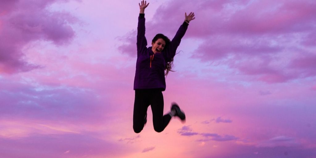 Energized woman jumping in the air with arms up