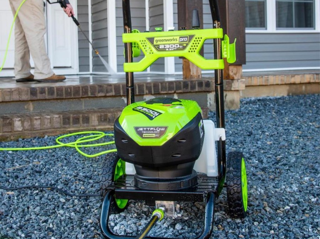 man using green power washer outside home