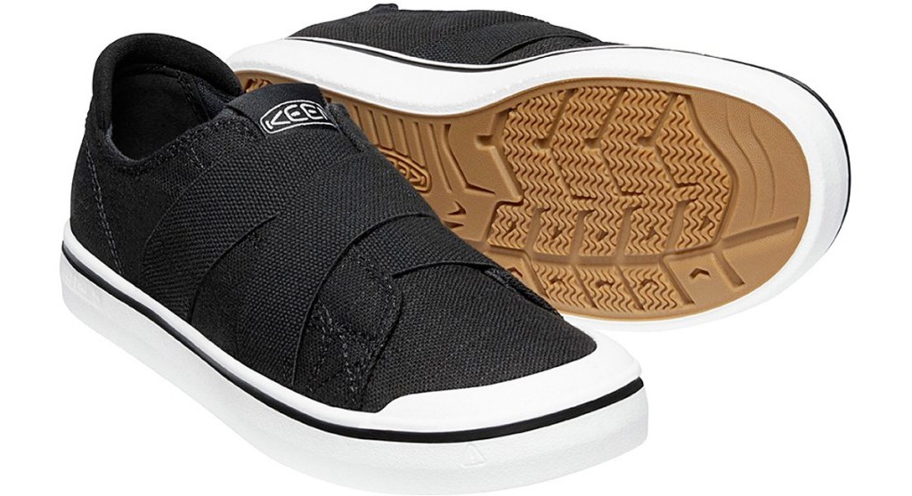 black canvas slip on sneakers with elastic straps across tongue 