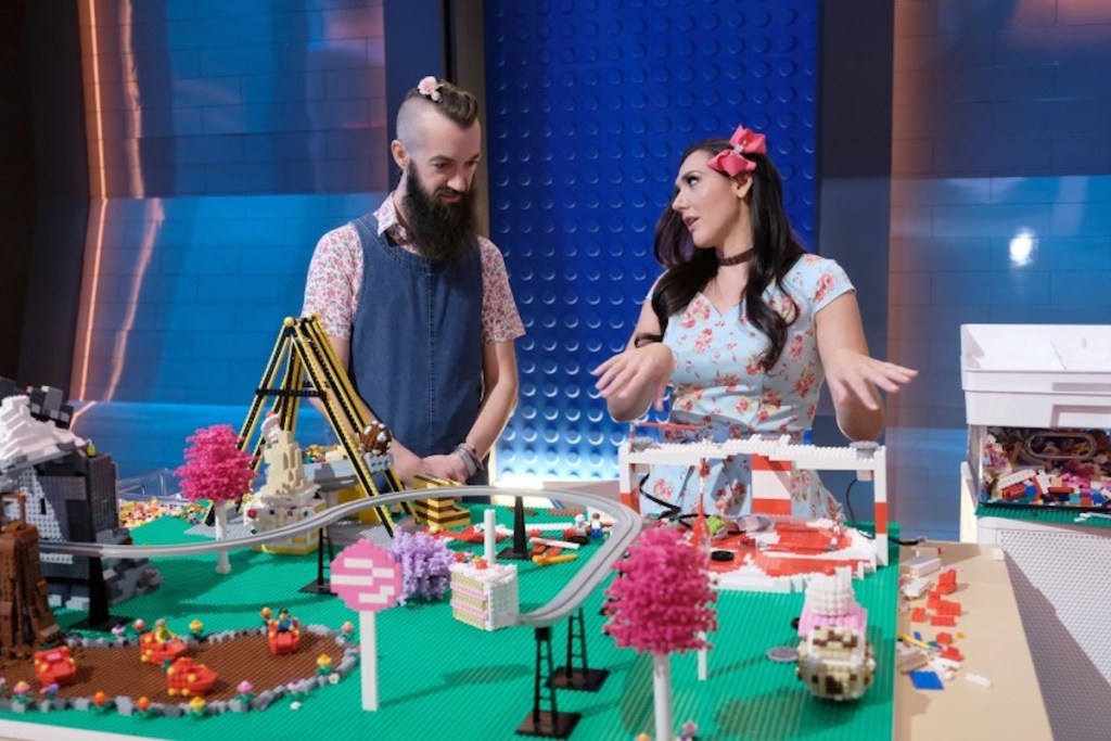 man and woman talking in front of huge lego display