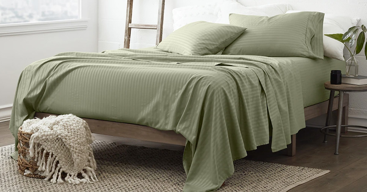 bed with sage green sheets on white area rug with basket and throw blanket in front of it