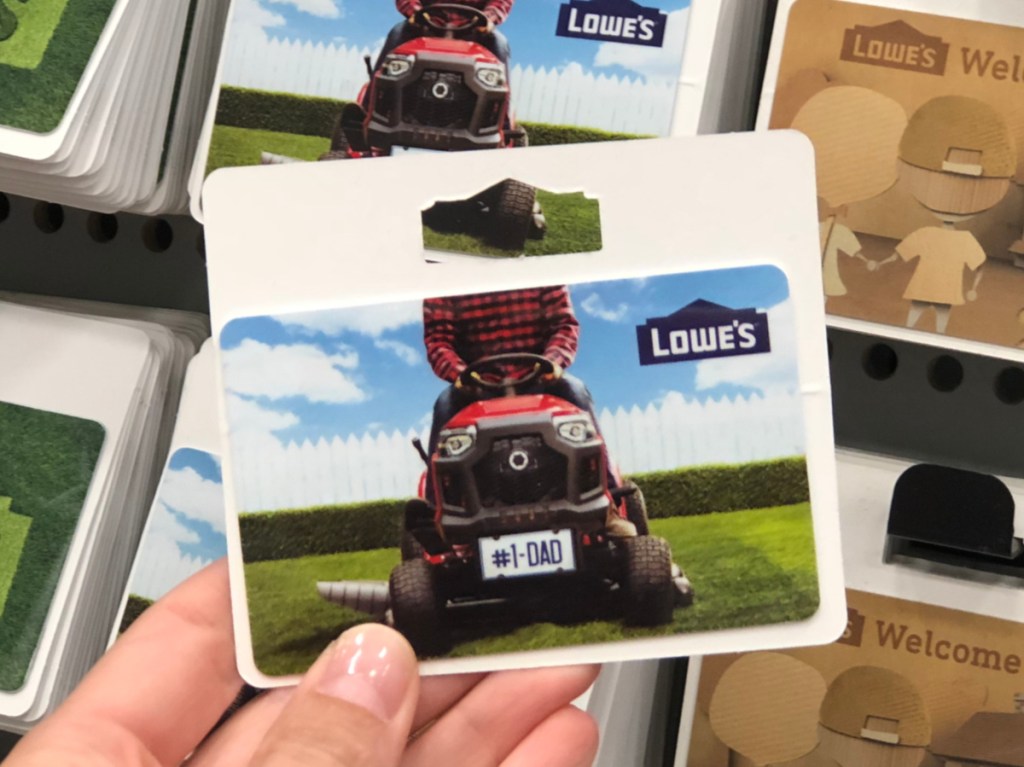 hand holding Lowe's gift card in front of gift card display