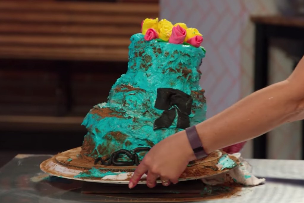 hands placing blue tiered cake on table 