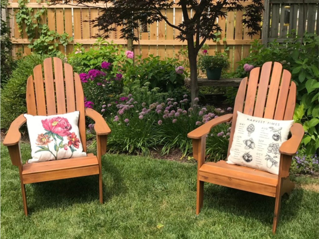two natural wood Adirondack chairs in grass