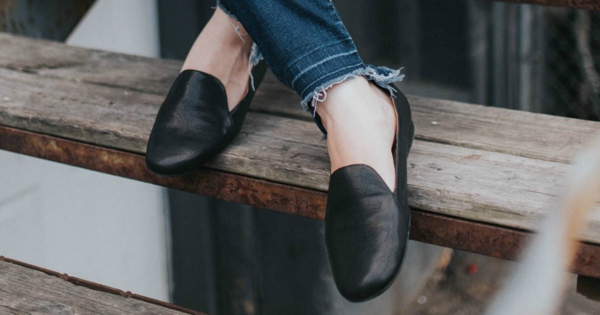 Woman sitting on wooden steps wearing black loafers