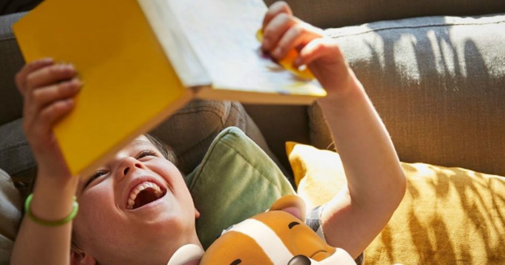 boy holding a book with a puppy in hus bed