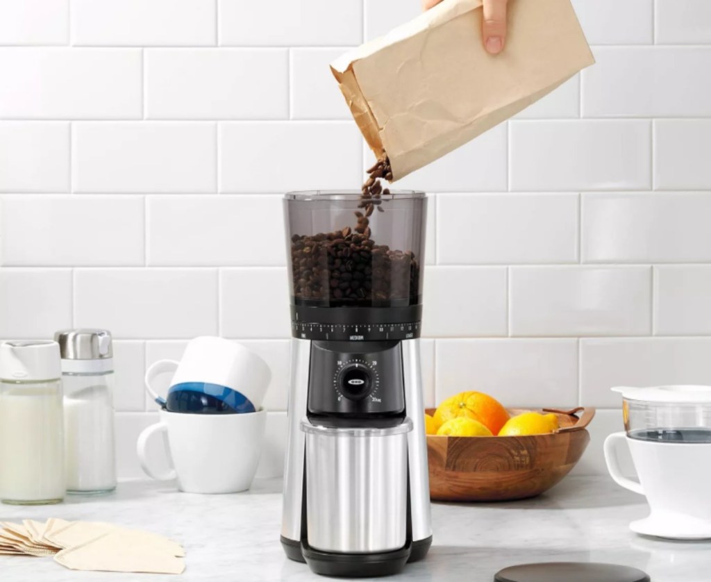 woman pouring coffee beans into a grinder