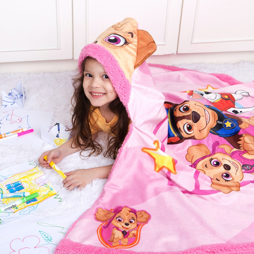 girl laying on the floor wearing Paw Patrol Snuggle Wrap in Skye coloring