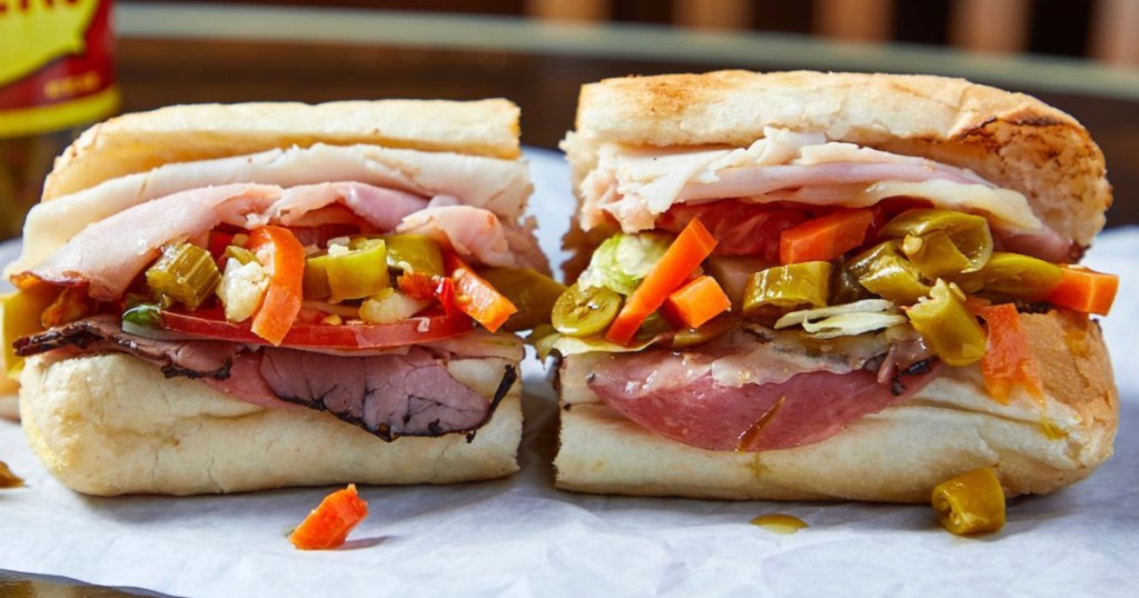 sandwich with meat and veggies cut in half on parchment paper
