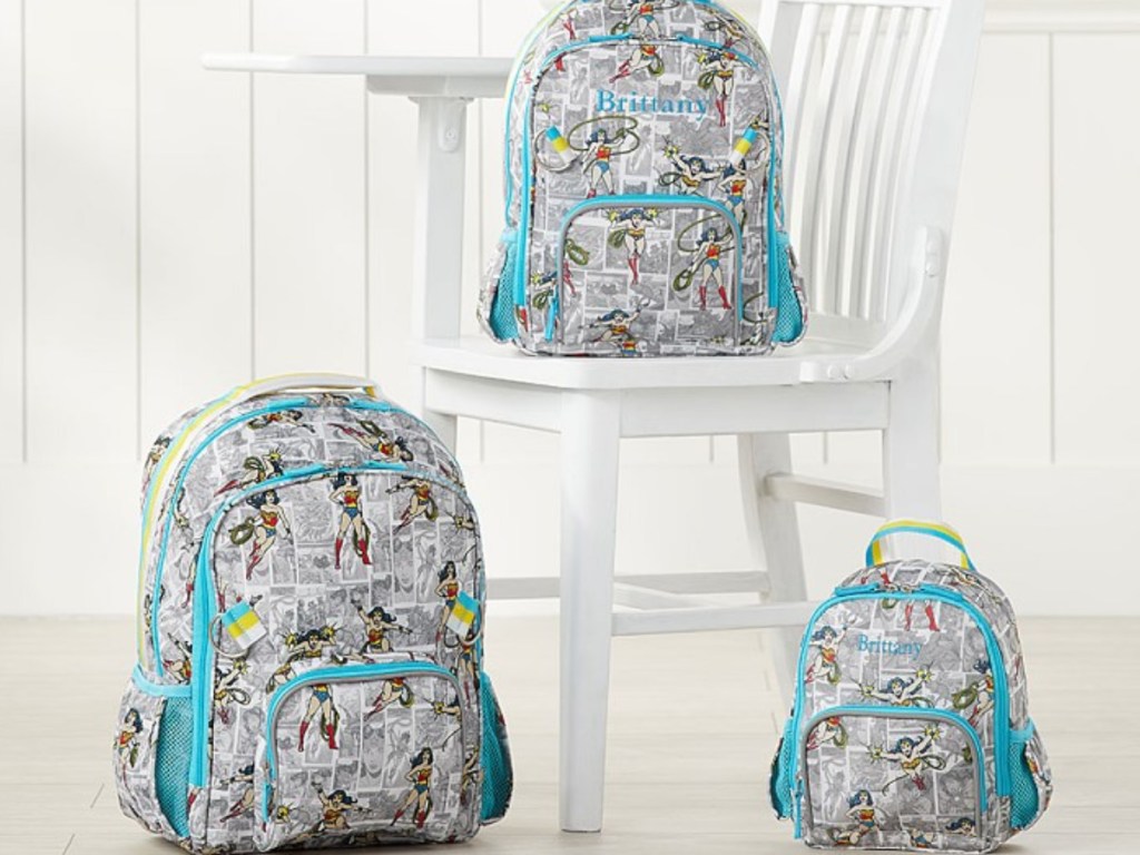 3 pottery barn wonder woman backpacks sitting next to each other and a white chair