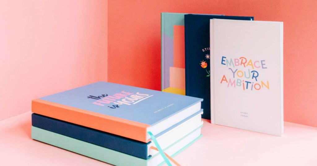 stack of journals next to journals leaning against a wall