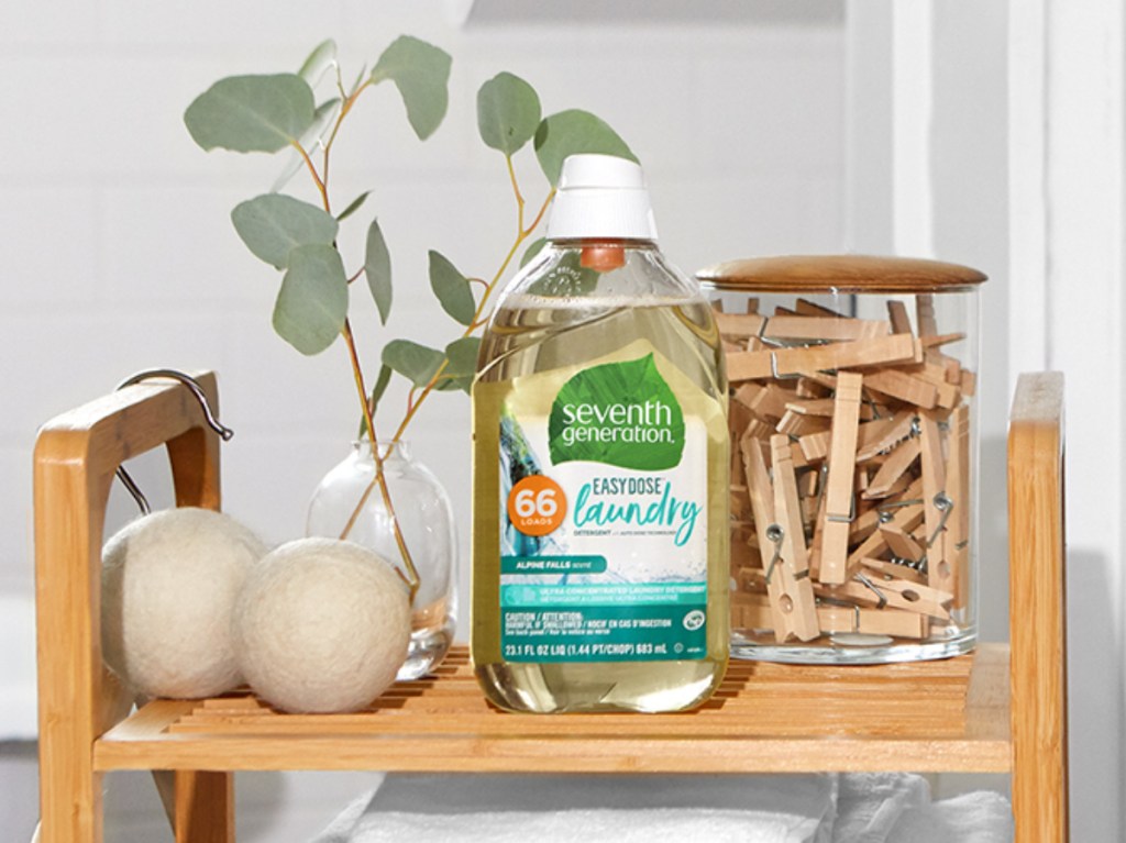 large bottle of laundry detergent on table with plants, towels, and clothespins
