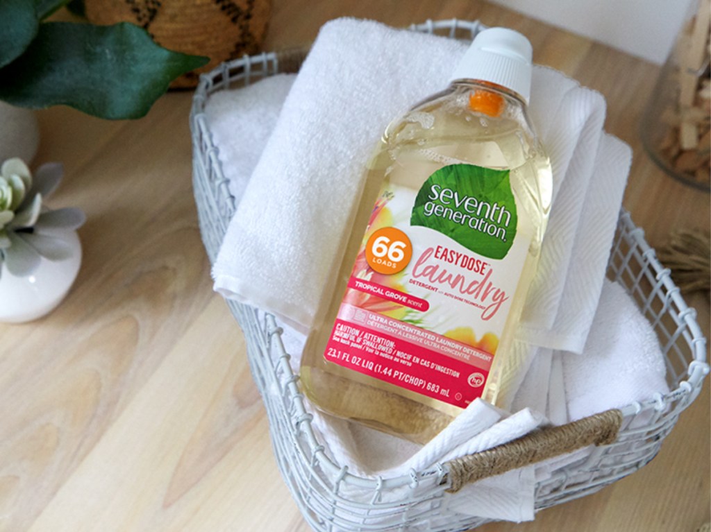 large bottle of laundry detergent on pile of towels in bin on floor in home
