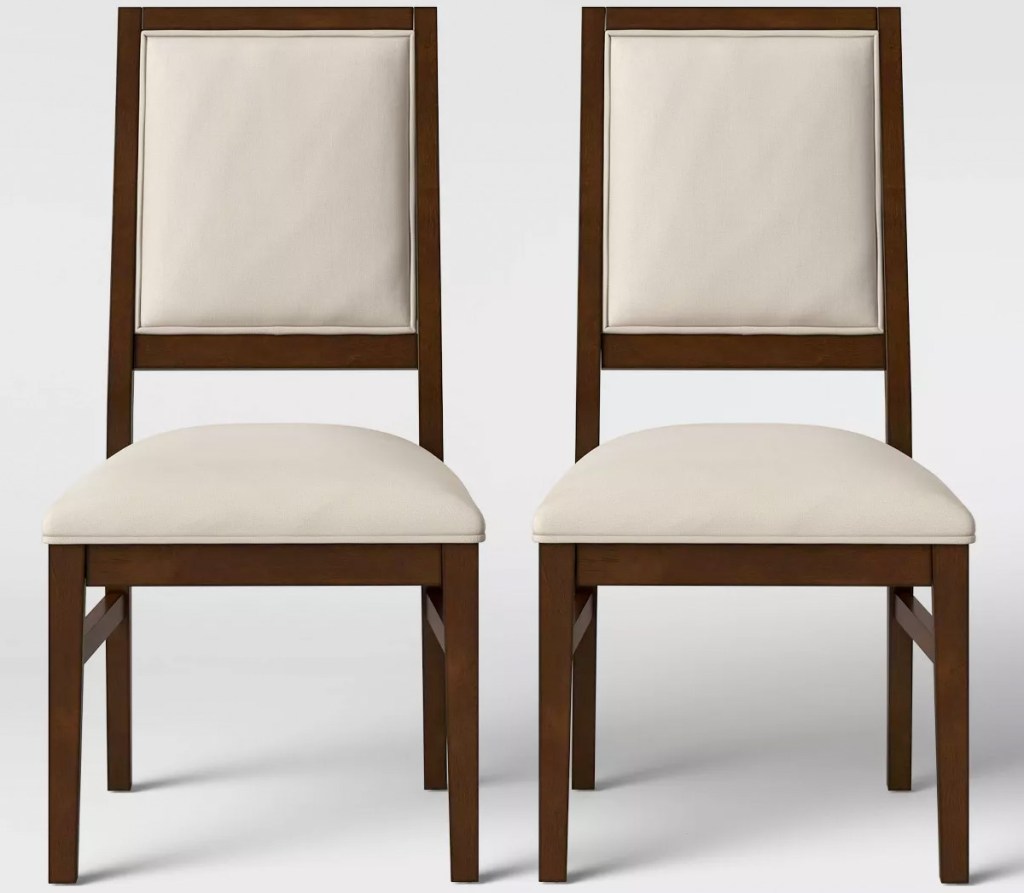 two white dining chairs with wooden legs and wood trim