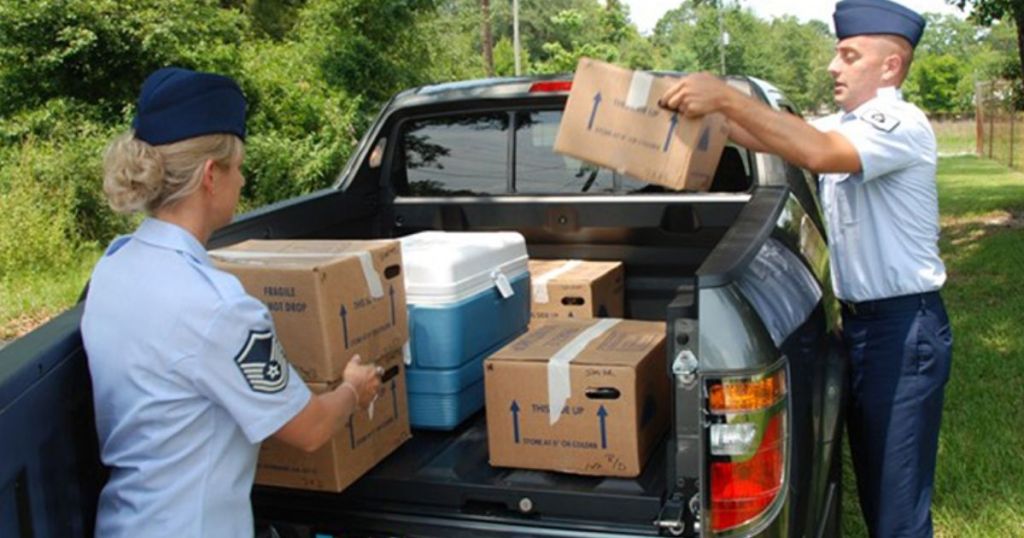 Men in Air Force uniforms placing boxes of food in the back of a truck for delivery