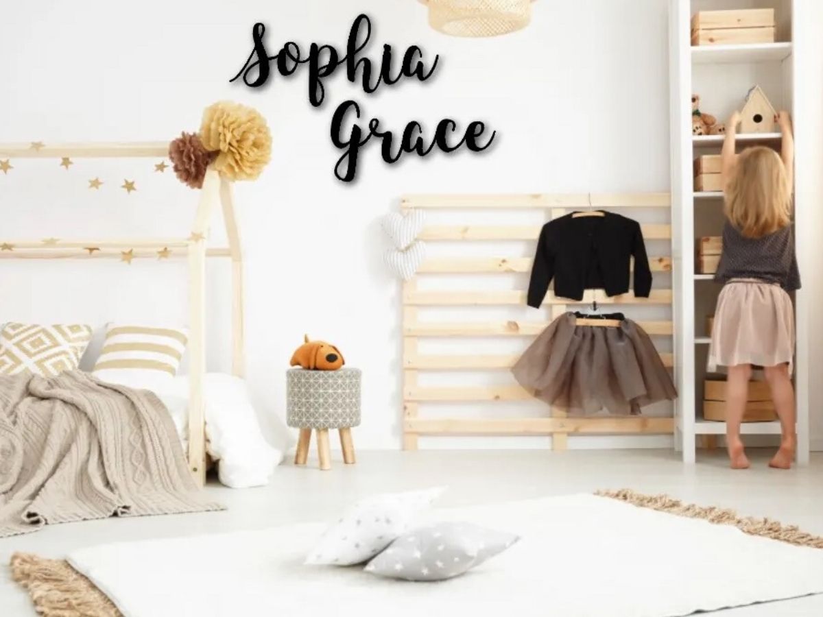 Little girl in bedroom with large personalized first and middle name on wall