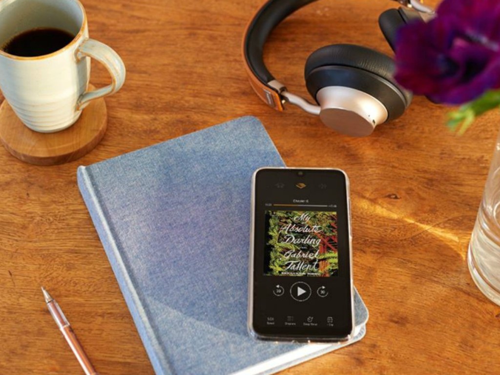book on table with phone, headphones and coffee