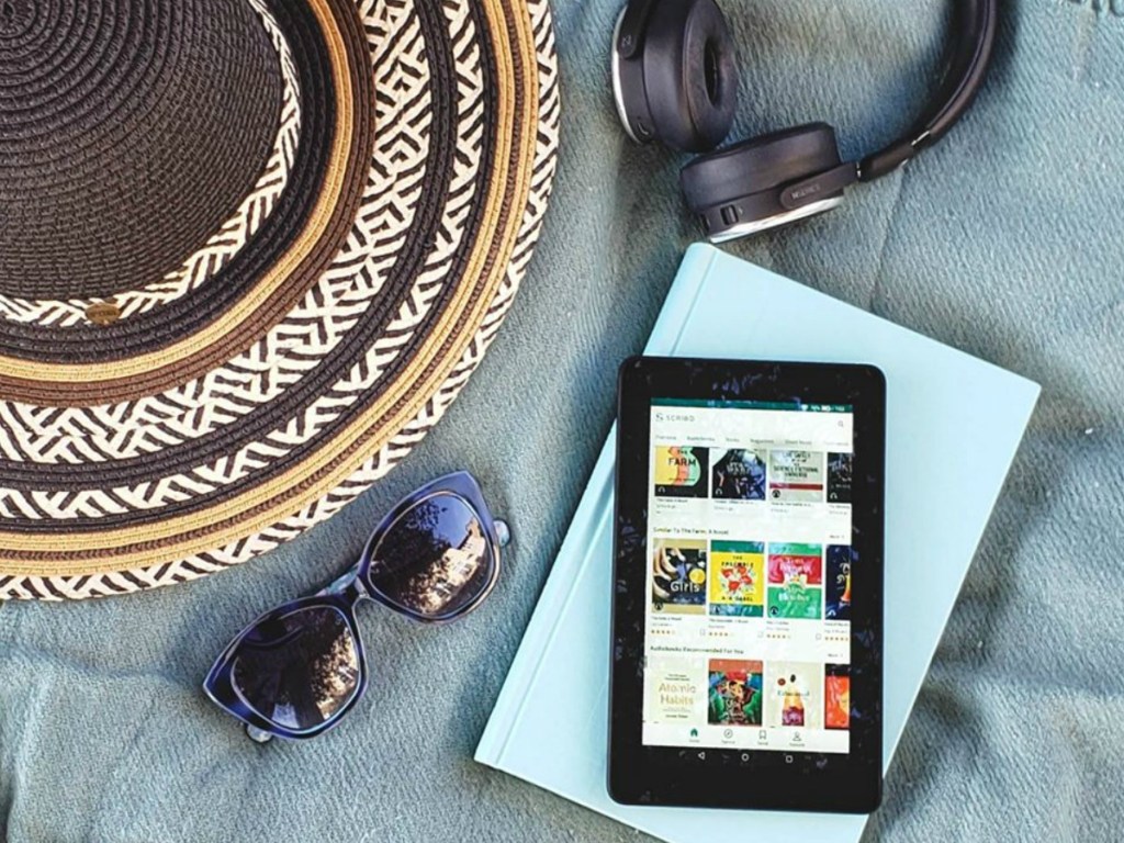 tablet, book, headphones, hate and sunglasses on blanket outdoors