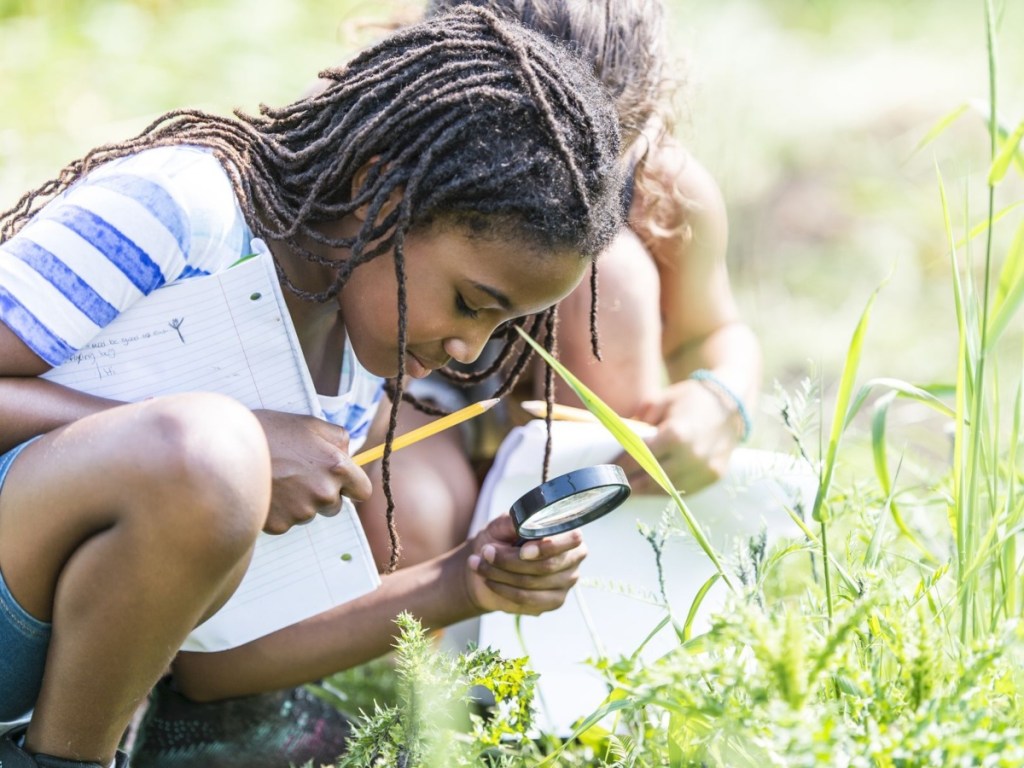 Boy using magnifying glass outside