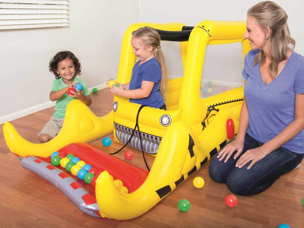 mom playing with kids in a bulldozer ball pit